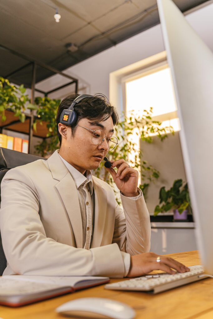 Businessman with headset working on computer in modern office setting.